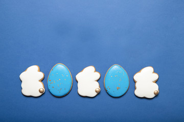 Easter cookies on a plate on a blue background. Place for text. Easter bunny. Easter eggs.