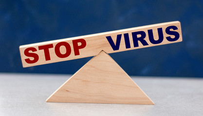 the concept of the balance of stop words and the virus on wooden scales on a blue background