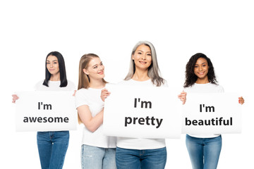 happy multicultural women in jeans holding posters with lettering isolated on white