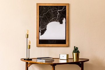 Interior design of sitting room with stylish wooden table, gold clock, table lamp, books and elegant personal accessoreis. Brown wooden mock up poster map on the beige wall. Home decor. Template.