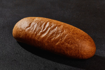 Fresh, tasty baked bread against black background with copy space. Rural cuisine or bakery. Close-up