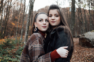 Fototapeta premium Two girls young model walk. Two pretty cuter teenagers shares. Best friends wearing stylish outfit, autumn outdoor.