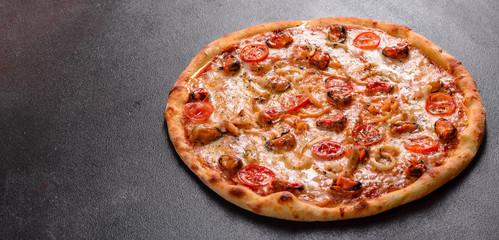 Tasty sliced pizza with seafood and tomato on a concrete background