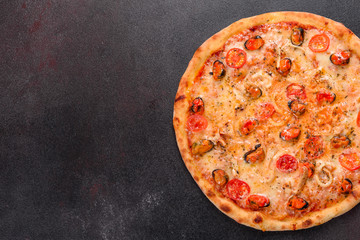 Tasty sliced pizza with seafood and tomato on a concrete background