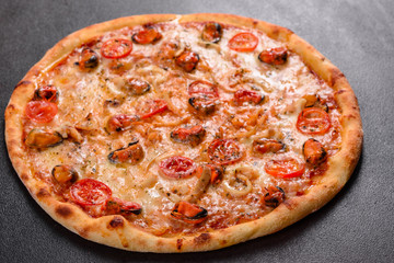 Tasty sliced pizza with seafood and tomato on a concrete background