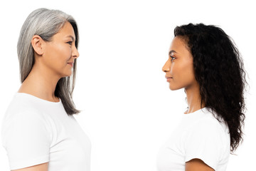 side view of happy african american and asian women looking at each other isolated on white