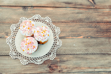 Happy Easter cake with sprinkles on white glaze. Easter cake on old rustic wooden board, lace cloth. Festive homemade bakery, spring holiday preparation. Selective focus, free text space.