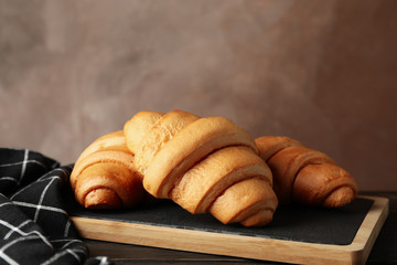 Board with croissants on wooden table with towel, close up