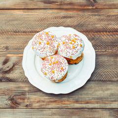 Happy Easter cake with sprinkles on white glaze. Easter cake on old rustic wooden board, lace cloth. Festive homemade bakery, spring holiday preparation. Selective focus, free text space.