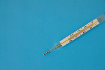 The medicine. Healthcare On a blue background a glass thermometer for measuring the temperature of a person’s body.