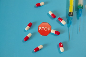 On a blue background, syringes for injection, white-red capsules, tablets.