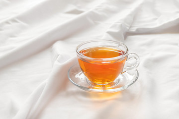 Morning cup of tea on white bed sheet with copy space. Good morning concept.