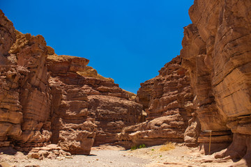 soft focus desert sand stone canyon rocks passage trail between walls foreshortening from below on vivid blue sky background