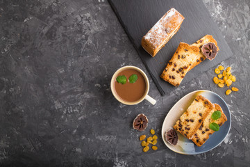 Homemade cake with raisins, dried persimmon and a cup of hot chocolate on a black concrete background. top view, copy space.