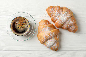 Cup of coffee and croissants on wooden background, top view