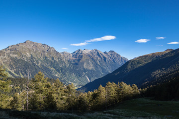 Fototapeta premium Panorama view of Swiss Alps in Grisons and aerial view of the Val Mesolcina valley and Mesocco town, on a sunny summer day on the Sentiero - Calanca hiking trail in Canton of Graubuenden, Switzerland