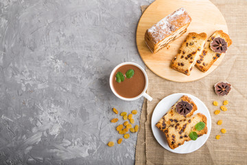 Homemade cake with raisins, dried persimmon and a cup of hot chocolate on a gray concrete background. top view, copy space.