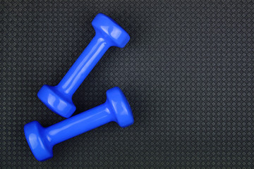 Fitness concept. Weight loss. Blue dumbbells isolated on grey yoga mat. With copy space for text