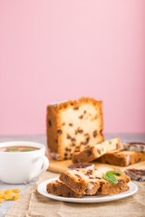 Homemade cake with raisins, dried persimmon and a cup of hot chocolate on a gray and pink background. side view, selective focus.