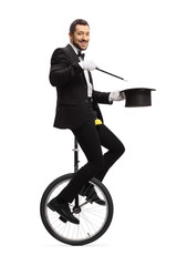 Magician with a wand riding a unicycle and smiling at camera