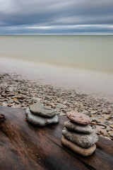 Rocky seashore of the Baltic Sea during the day. Long Exposure. Blurred water. An interesting clody sky.