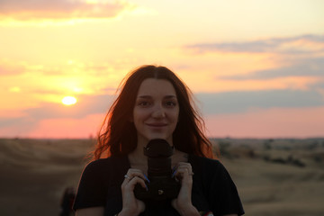 Smiling young woman holding a professional photo camera
