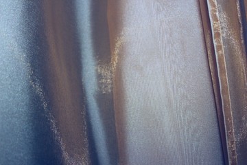 Silver-gray fabric background with pleats. Shiny silk, satin, organza.