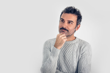 Portrait of  handsome and brown thinking man with mustache and  gray sweater. Gray background. Copy...