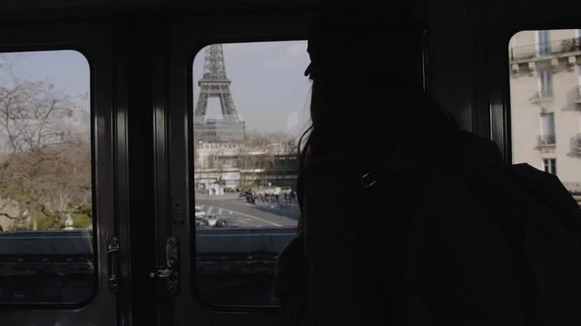 Silhouette of young tourist woman riding metro train, watching amazing Paris Eiffel Tower through the window slow motion