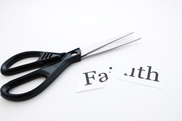 the word faith is written on a piece of paper and cut with scissors lying