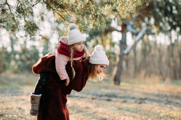 Mother and daughter have fun in the pine forest.