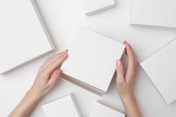 Mock up of white present box in women's hands on the white background surrounded with many...