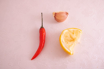 vegetarian concept, chilli pepper, garlic and lemon on pink paper , top view food