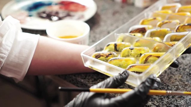 Painting plastic palette with yellow edible dye for chocolate sweets