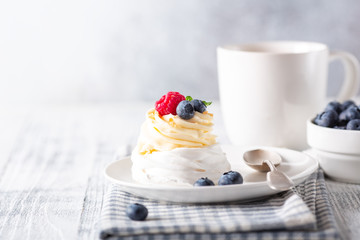 Delicious Pavlova cake with whipped cream and fresh berries. White cup of coffee. Selective focus