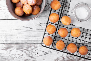 Golden round donuts on the black lattice on the white wooden table