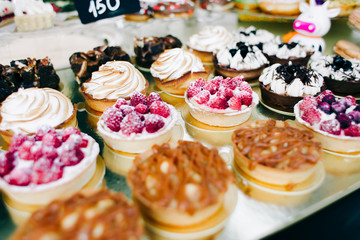 a lot of beautiful delicious cakes with nuts and berries at the street fair