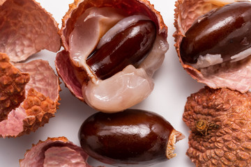 red-orange peeled prickly lychee fruit with a seed, on a white background