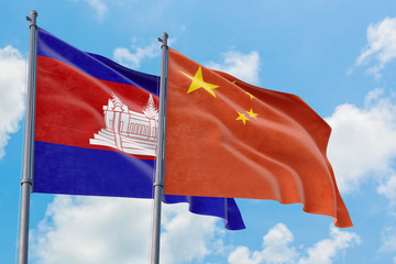 China and Cambodia flags waving in the wind against white cloudy blue sky together. Diplomacy...