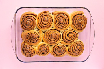 Freshly backed  Cinnamon Rolls Sweet or Cinnabons in transparent backing form on light pink background, top view
