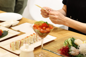 Obraz na płótnie Canvas Sushi and rolls and woman with chopsticks