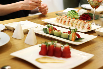 Sushi and rolls and woman with chopsticks