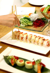 Sushi and rolls and woman with chopsticks