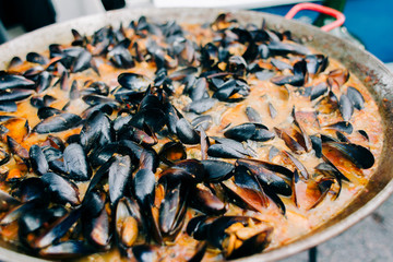 delicious oysters cooked in a large frying pan in a creamy tomato sauce at a street market