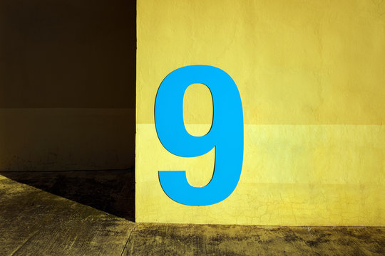 Orange wall illuminated at sunset with the number 9 on it.