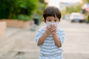 Child wearing a protective face mask on a city street with air pollution. Facial hygienic mask for Safety outdoor environmental awareness concept And protect disease virus against germs dustpm2.5