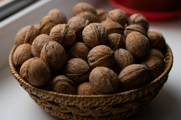 Small wicker basket filled with walnuts on a white background
