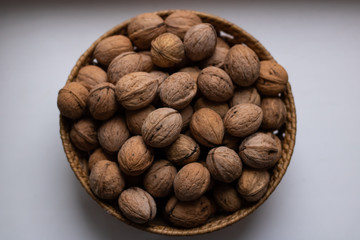  Small wicker basket filled with walnuts on a white background