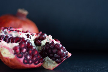 Fresh pomegranate broken on black background lentil pasta with broccoli defocus foreground