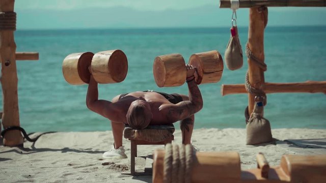 Fitness man training on the beach. Athlete doing cross fitness workout outdoor. Sport fit exercise. Eco gym